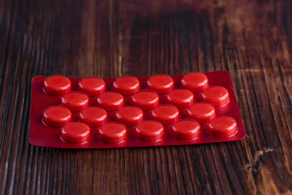 Ahşap arka plan üzerinde kırmızı bir blister Tablet