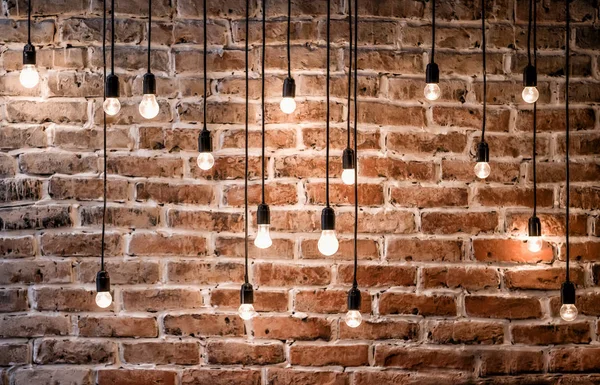 Incandescent bulbs on brick wall background in loft style — Stock Photo, Image