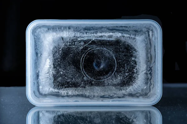 Camera frozen in ice in plastic box — Stock Photo, Image