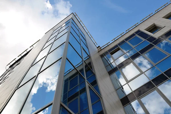 Looking up at a modern building faced with mirrored glass and me