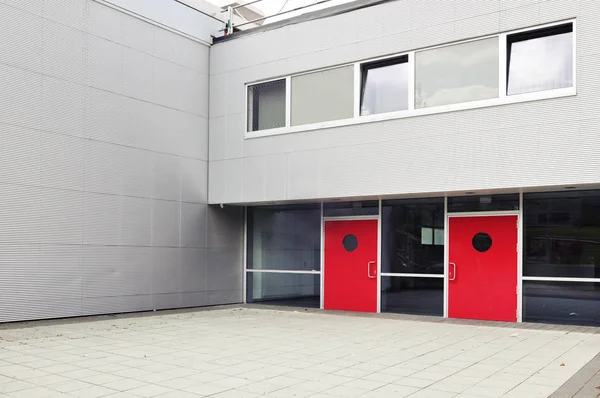 Edifício cinza moderno com portas vermelhas — Fotografia de Stock