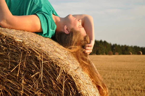 Red haired woman lying on the haystack Stock Picture