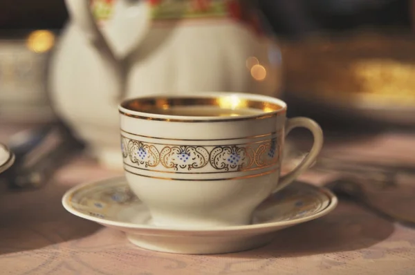 Vintage porcelain cup with golden ornament close up.