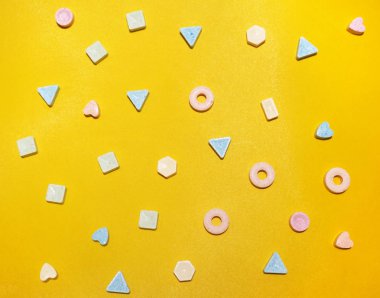 Çok çok renkli tatlı şekerler sarı bir arka plan üzerinde farklı şekiller.