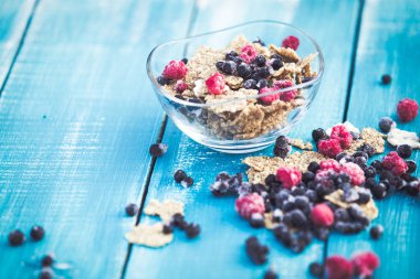 Mavi ahşap arka planda organik tahıl ve orman meyveleri