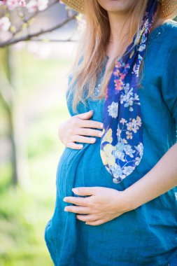 Bahar arkaplanındaki genç hamile kadın
