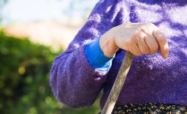 Yaşlı kadın elleri tahta sopanın üzerinde.