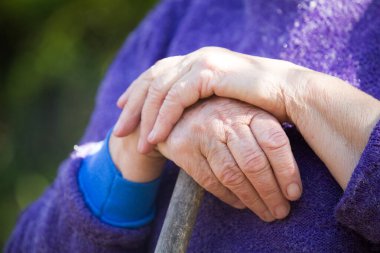 Yaşlı kadın elleri tahta sopanın üzerinde.