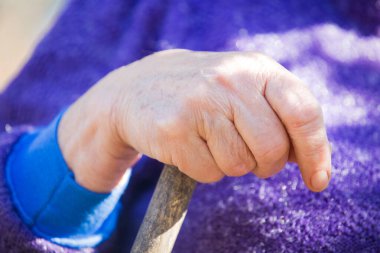 Yaşlı kadın elleri tahta sopanın üzerinde.