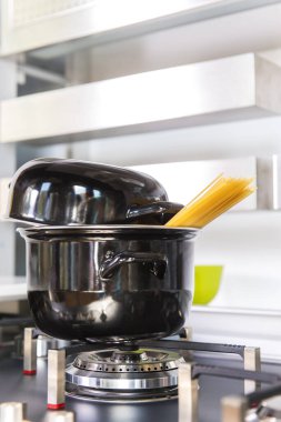 Çelik tavada spagetti kaynıyor. İtalyan çiğ spagettisi. Fırının üstünde bir tabak spagetti..