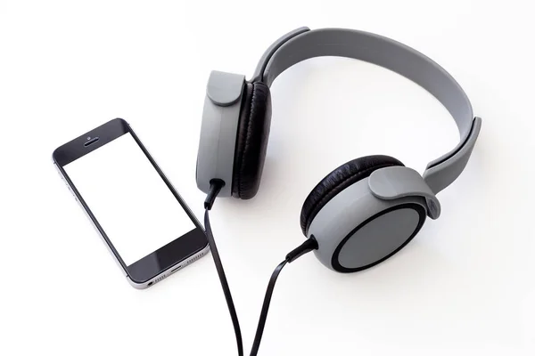 Matná šedá hudební sluchátka s smartphone izolované na bílém — Stock fotografie