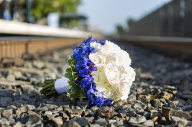 Tren raylarında çakılların üzerine bırakılmış beyaz gül buketi.