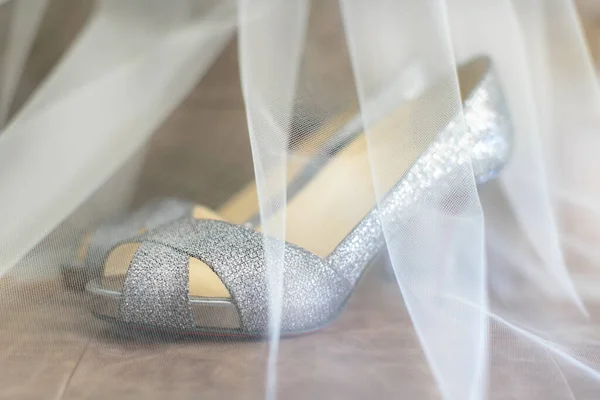 Toule wedding veil covering a pair of high-heeled bride shoes
