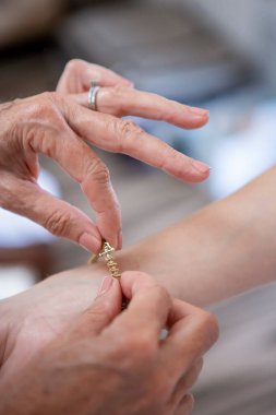 Düğünü için bileğine bilezik takarken, gelin ve annenin elleri.