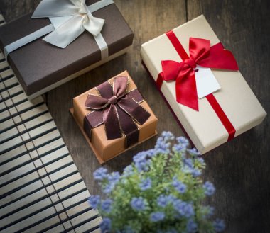 Üç kutuları ve saksıyı ahşap arka plan üzerinde hediye