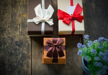 Üç kutuları ve saksıyı ahşap arka plan üzerinde hediye