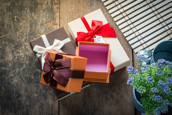 Trois boîtes cadeaux et pot de fleurs sur fond en bois — Photo