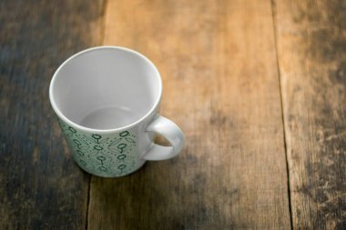 Ahşap zemin üzerine yeşil desenli beyaz Kupası