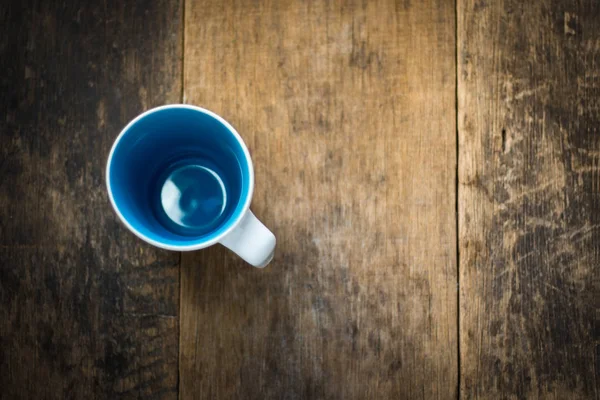 Weiße Tasse innen blau auf hölzernem Hintergrund — Stockfoto