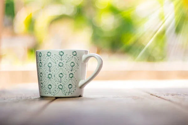 Weiße Tasse mit grünem Muster auf Holzgrund — Stockfoto