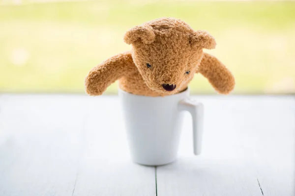 Relax Konzept. Teddybär mit weißem Kaffeebecher über grünem Bokeh-Hintergrund. — Stockfoto