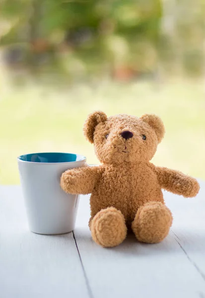 Relax Konzept. Teddybär mit weißem Kaffeebecher über grünem Bokeh-Hintergrund. — Stockfoto