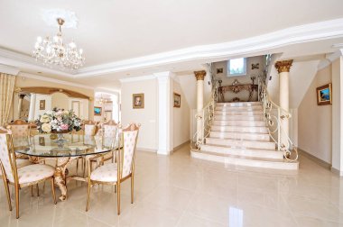 Yemek salonu, mermer zemin ve sahte raylı merdivenleri olan lüks bir iç mekan..