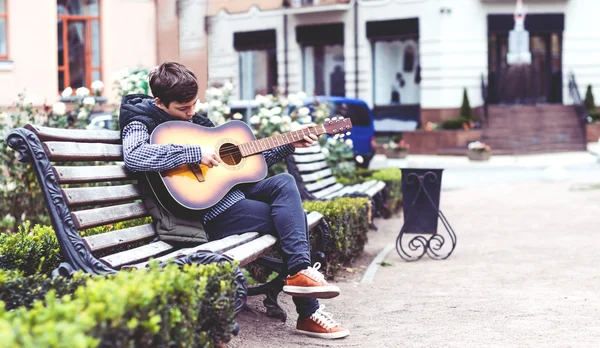 Ung man spelar på akustisk gitarr utomhus — Stockfoto