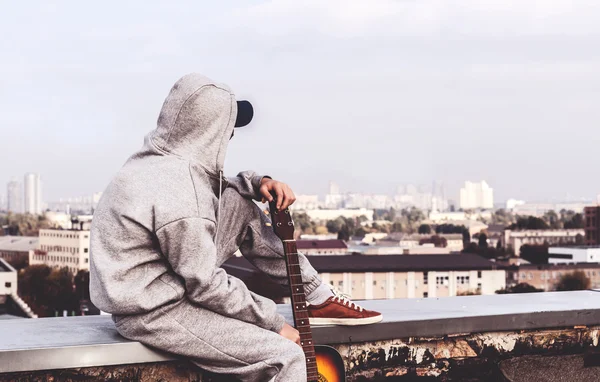 Молодий чоловік на даху з гітарою — стокове фото