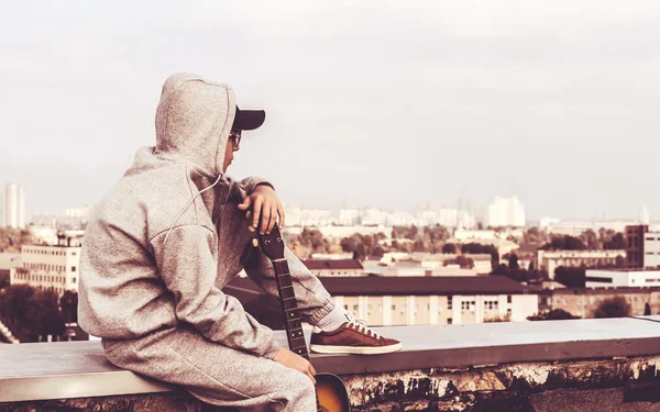 Młody człowiek na dachu z gitarą — Zdjęcie stockowe