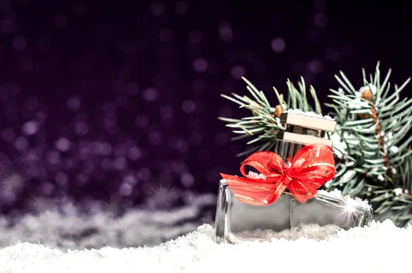 Perfume bottle in the snow on a purple background — Stock Photo, Image