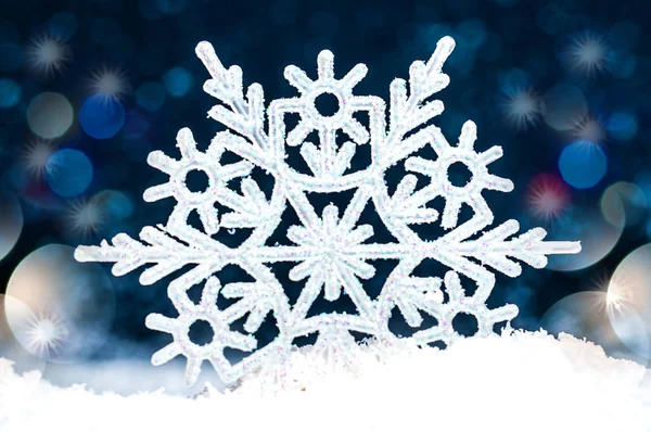Snowflake in the snow on a dark blue background — Stock Photo, Image