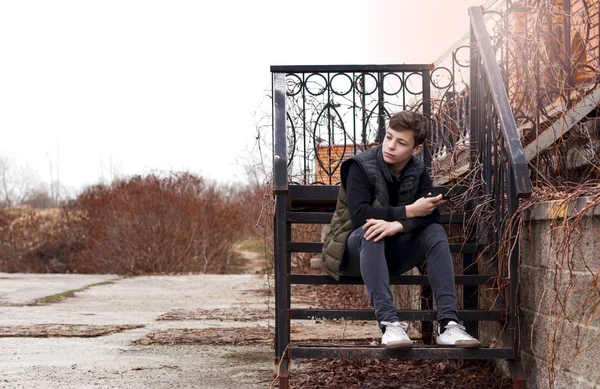Грустный молодой человек, сидящий на ступеньках — стоковое фото