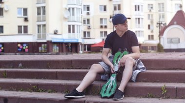 Bir kaykay üzerinde bir şehir sokak ile genç adam