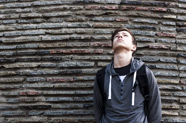 Serious young man near the wall of stones — Stock Photo, Image