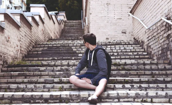 Молодой человек сидит на лестнице на городской улице — стоковое фото