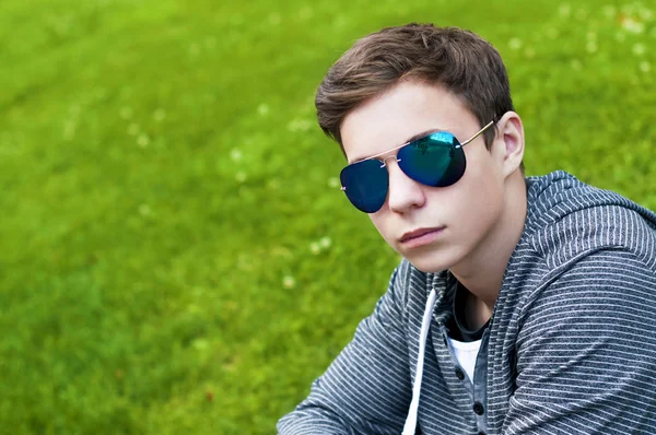 Beau jeune homme avec des lunettes assis sur l'herbe — Photo