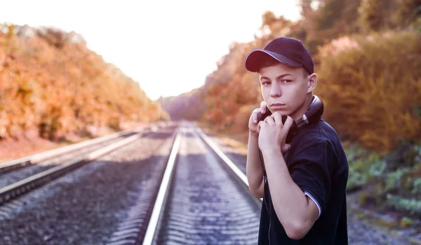 Підліток з навушниками слухає музику на залізничних коліях — стокове фото