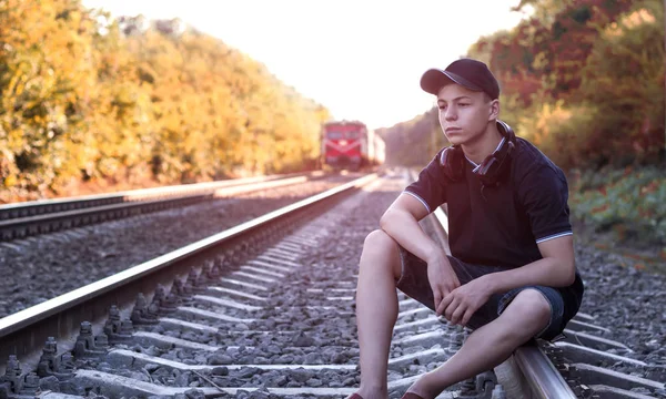 Adolescente com fones de ouvido ouve música nas trilhas ferroviárias — Fotografia de Stock