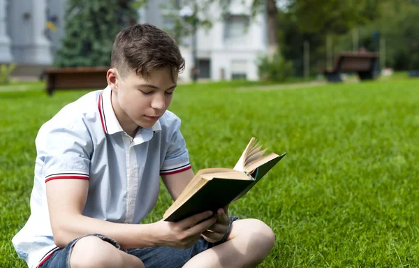 Genç adam çimlere oturup kitap okumak