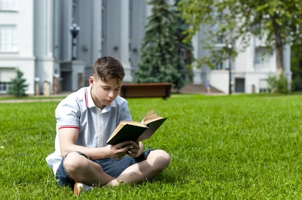 Genç adam çimlere oturup kitap okumak