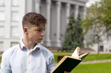 Gri building yakınındaki onun elinde bir kitapla genç adam