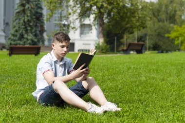 Genç adam çimlere oturup kitap okumak