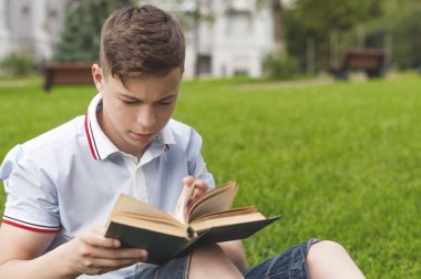 Genç adam çimlere oturup kitap okumak