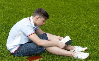 Genç adam çimlere oturup kitap okumak