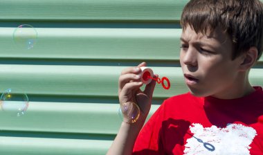 Sabun köpüğü yeşil bir arka plan üzerinde olan küçük çocuk