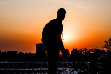 Gün batımı arka plan üzerinde genç bir adam silüeti