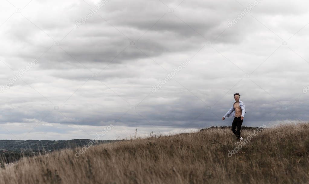man who feels free in a field on a hill