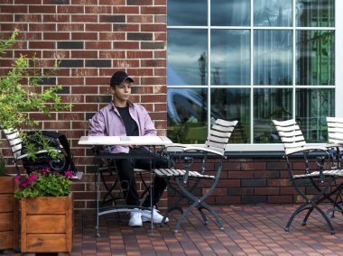 mutlu genç adam bir duvarının yakınında bir masada oturuyor