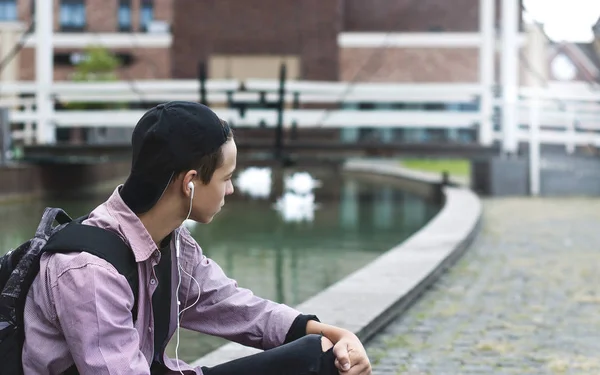 Joven escuchando música sentado en la acera — Foto de Stock